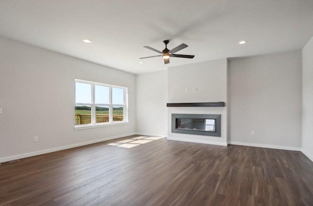 unfurnished living room with dark wood finished floors, baseboards, visible vents, and a ceiling fan