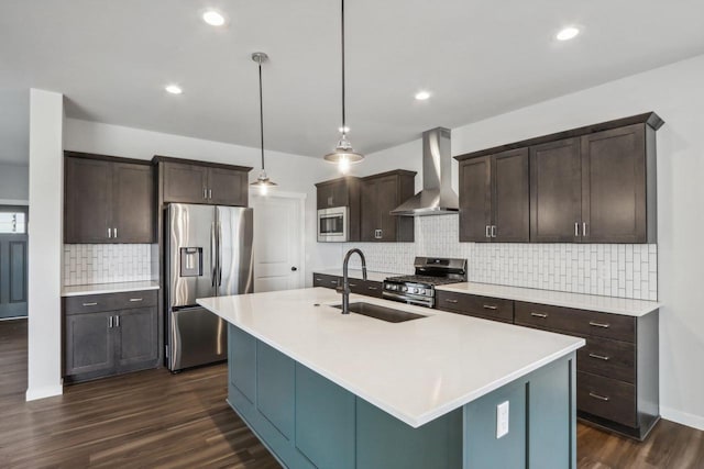 kitchen featuring dark wood finished floors, a sink, dark brown cabinets, appliances with stainless steel finishes, and wall chimney exhaust hood