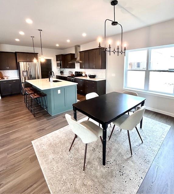 dining area featuring baseboards, wood finished floors, an inviting chandelier, and recessed lighting