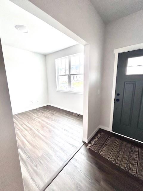 entrance foyer with baseboards, visible vents, and wood finished floors