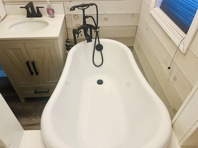 bathroom with a tub, wood walls, and vanity