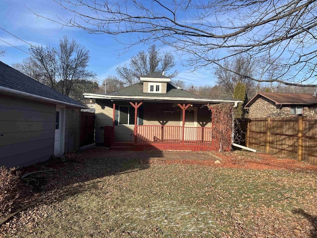 back of house featuring covered porch and a lawn