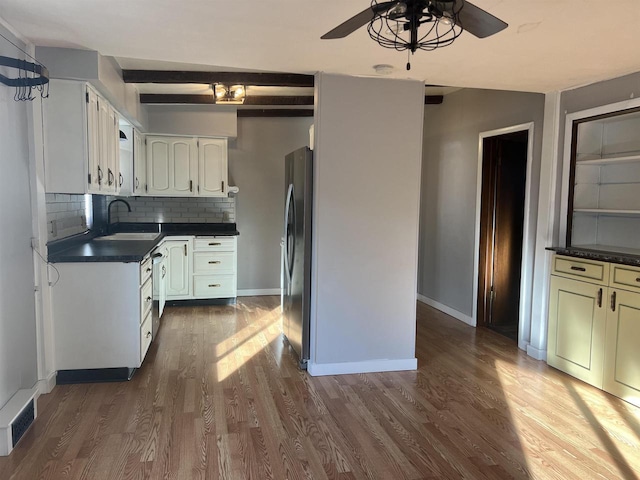 kitchen featuring beamed ceiling, tasteful backsplash, sink, white cabinets, and stainless steel appliances