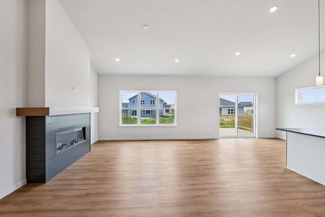 6635 Royal View Dr, Deforest, WI 53532 - unfurnished living room featuring light wood-style floors, a glass covered fireplace, recessed lighting, baseboards, and vaulted ceiling