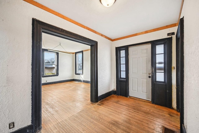 foyer entrance with crown molding and light wood-type flooring