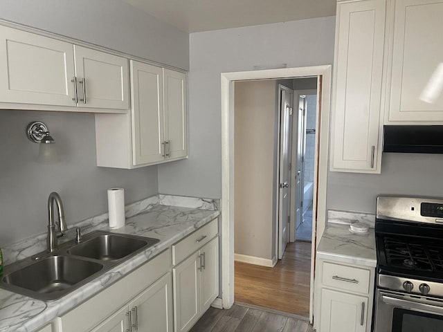 kitchen with white cabinetry, sink, dark hardwood / wood-style floors, ventilation hood, and stainless steel range with gas cooktop