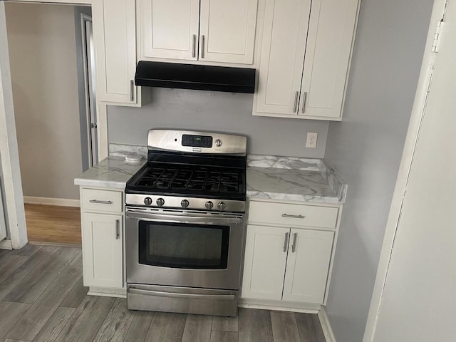 kitchen with light stone counters, white cabinets, dark hardwood / wood-style flooring, and stainless steel gas range oven