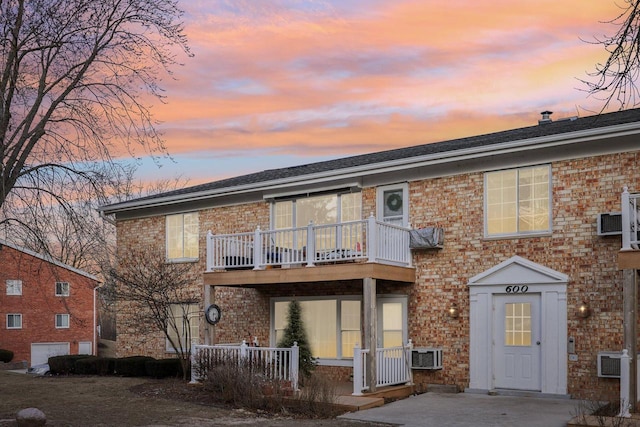 back house at dusk with a balcony and central AC unit