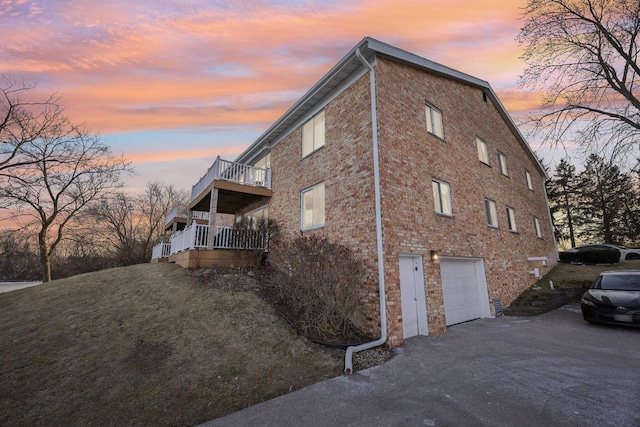 property exterior at dusk with a balcony, a yard, and a garage