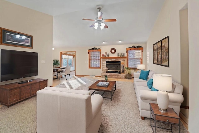 living room featuring a stone fireplace, light carpet, ceiling fan, and lofted ceiling