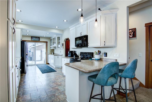 kitchen featuring black appliances, decorative light fixtures, a kitchen bar, white cabinetry, and kitchen peninsula