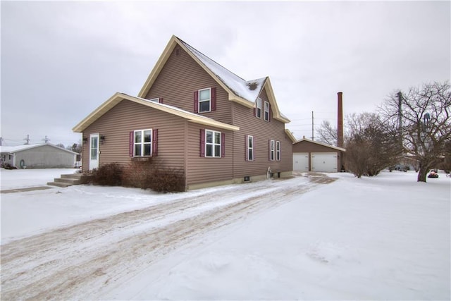 snow covered property with a garage and an outdoor structure