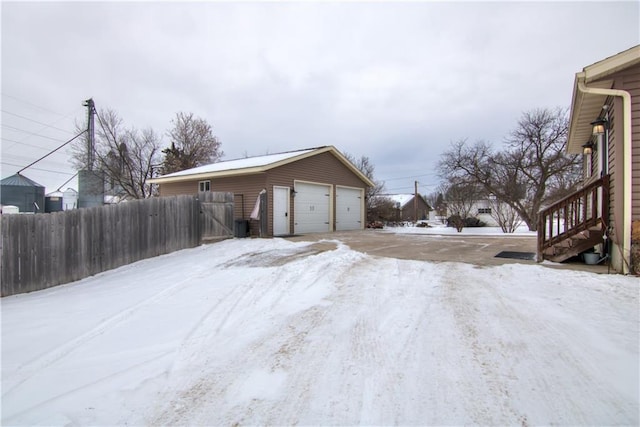 snow covered property with a garage and an outbuilding