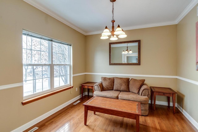 living area with crown molding, a chandelier, and light wood-type flooring