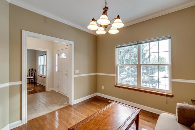 entryway with hardwood / wood-style flooring, ornamental molding, and a notable chandelier