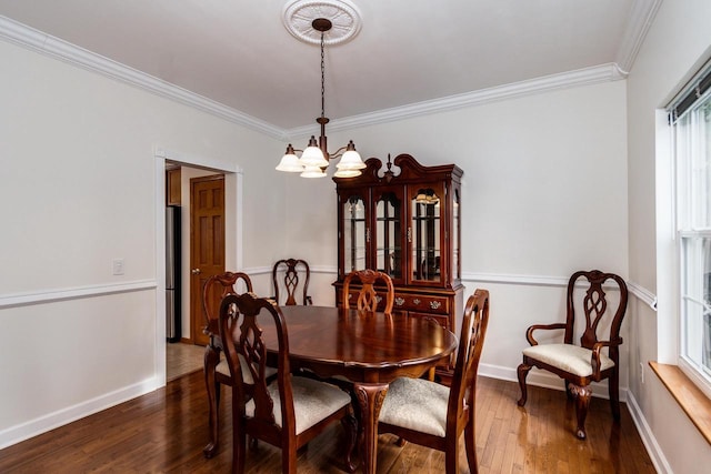 dining area featuring ornamental molding, dark hardwood / wood-style flooring, and an inviting chandelier