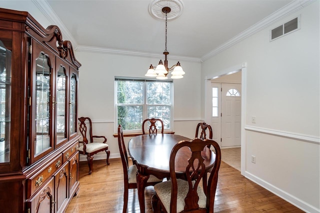 dining room featuring crown molding, light wood-type flooring, and a chandelier