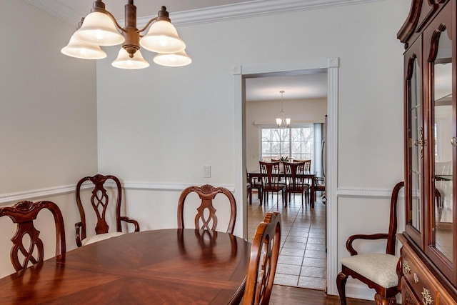 tiled dining area featuring an inviting chandelier and crown molding