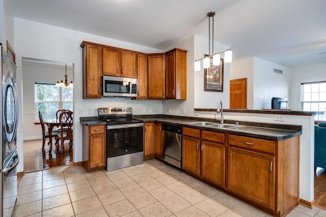 kitchen with pendant lighting, stainless steel appliances, kitchen peninsula, and sink