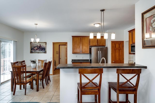 kitchen with sink, a breakfast bar area, light tile patterned floors, appliances with stainless steel finishes, and pendant lighting