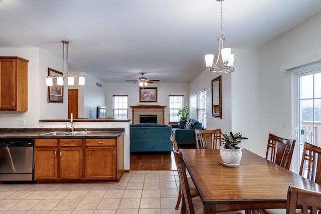 kitchen with a tile fireplace, dishwasher, sink, and decorative light fixtures