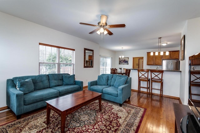 living room with dark wood-type flooring and ceiling fan with notable chandelier