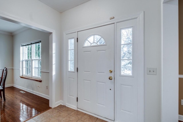 foyer entrance featuring crown molding, a healthy amount of sunlight, and light hardwood / wood-style flooring