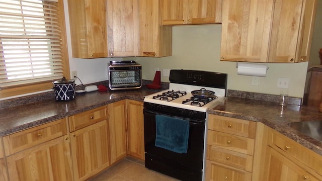 kitchen featuring light tile patterned floors and gas range