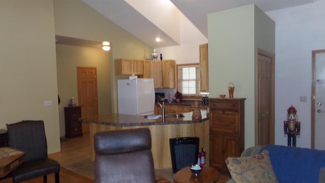 kitchen featuring white fridge, sink, kitchen peninsula, a breakfast bar area, and lofted ceiling