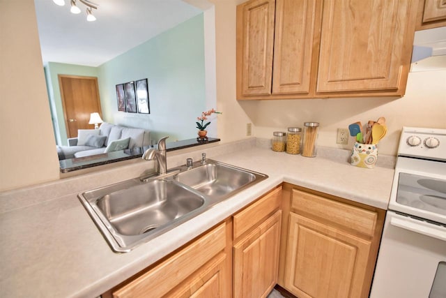 kitchen featuring white range, light brown cabinetry, sink, and kitchen peninsula