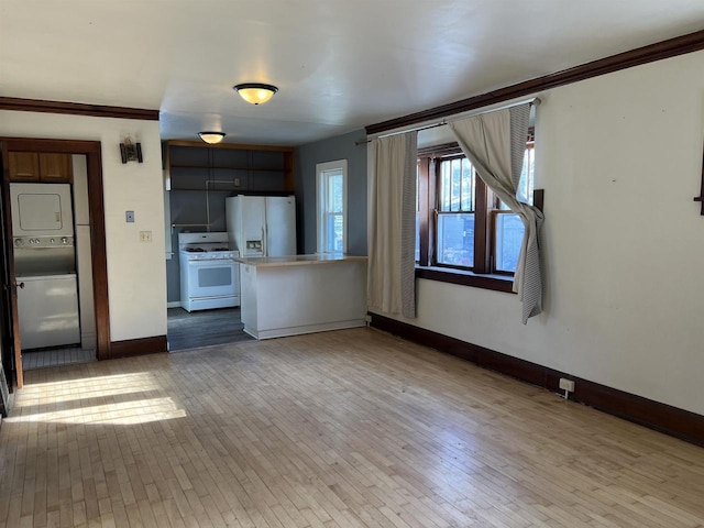 kitchen with kitchen peninsula, white appliances, wood-type flooring, and stacked washer and dryer