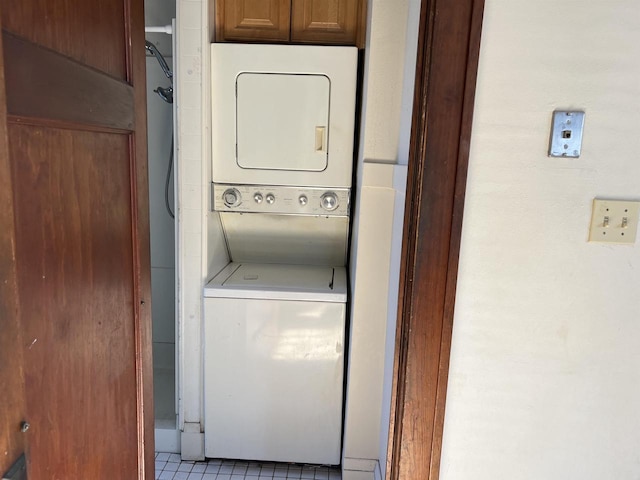 laundry area featuring light tile patterned floors and stacked washer and clothes dryer