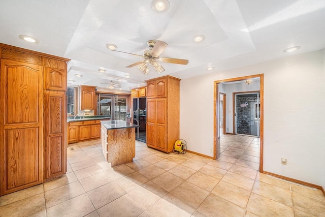 kitchen featuring ceiling fan, a center island, a breakfast bar area, and a tray ceiling