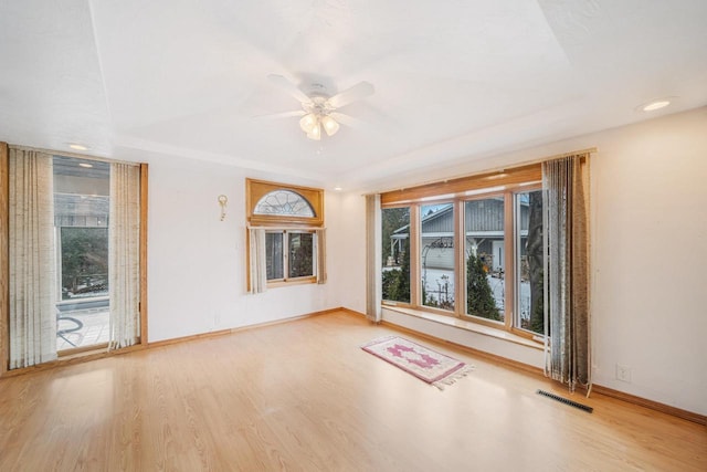 unfurnished room featuring ceiling fan, hardwood / wood-style floors, and a tray ceiling