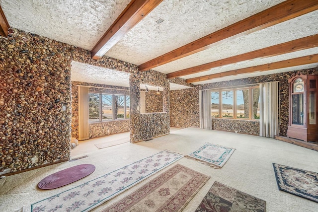 carpeted living room featuring plenty of natural light and beamed ceiling