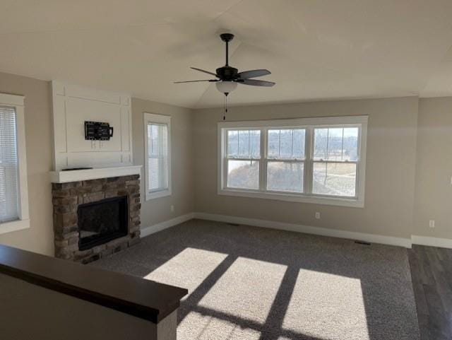 unfurnished living room featuring ceiling fan and a stone fireplace