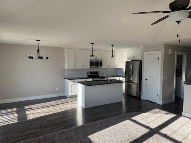 kitchen with appliances with stainless steel finishes, white cabinets, sink, pendant lighting, and a center island with sink