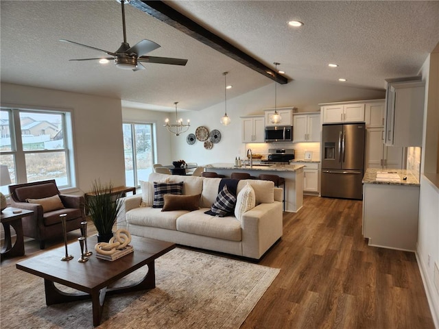 living room featuring ceiling fan with notable chandelier, a textured ceiling, dark hardwood / wood-style flooring, sink, and lofted ceiling with beams