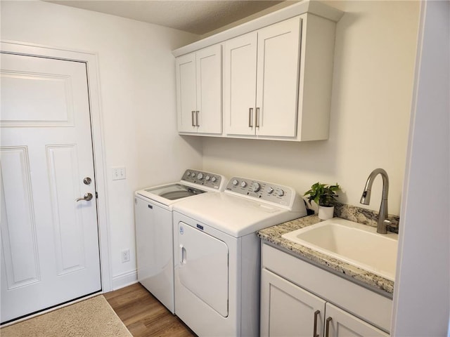 washroom featuring sink, washer and clothes dryer, light hardwood / wood-style flooring, and cabinets