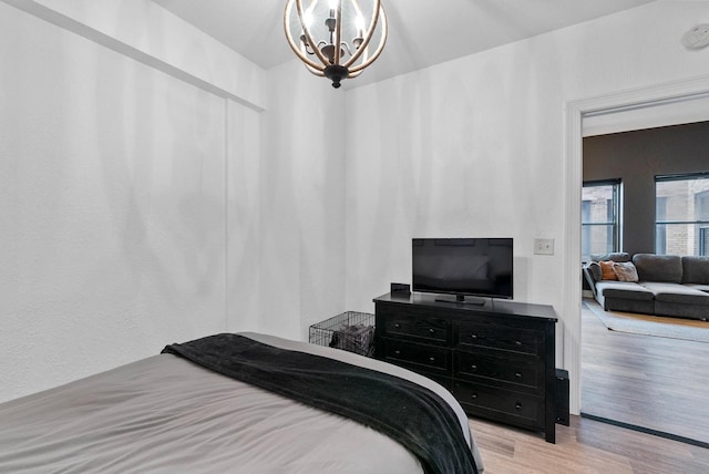 bedroom featuring an inviting chandelier and light wood-type flooring