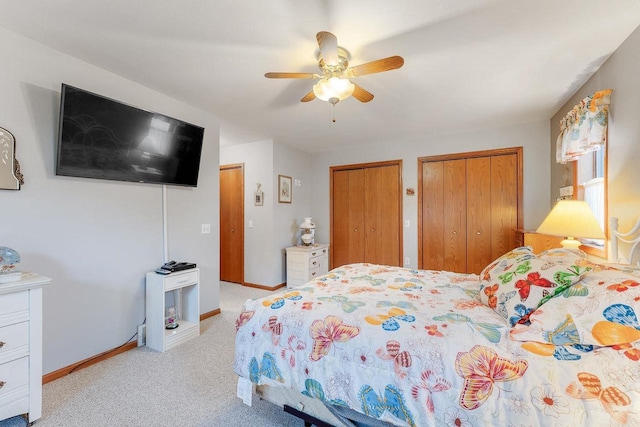 bedroom featuring light colored carpet, two closets, and ceiling fan