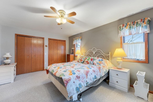 carpeted bedroom featuring multiple closets, ceiling fan, and multiple windows