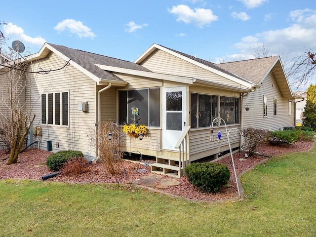 back of property with a yard and a sunroom