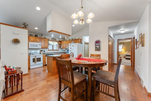 dining area featuring light wood-type flooring, vaulted ceiling, an inviting chandelier, and sink