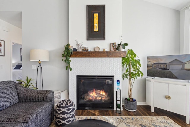 living room featuring a tiled fireplace and dark hardwood / wood-style flooring