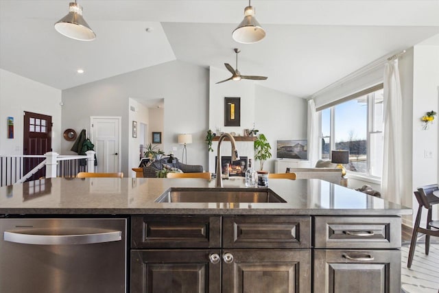 kitchen with lofted ceiling, sink, a kitchen island with sink, stainless steel dishwasher, and dark brown cabinets