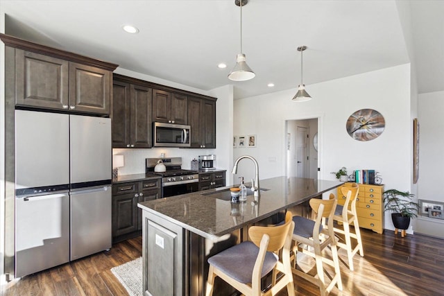 kitchen featuring sink, a breakfast bar, appliances with stainless steel finishes, a kitchen island with sink, and dark brown cabinetry