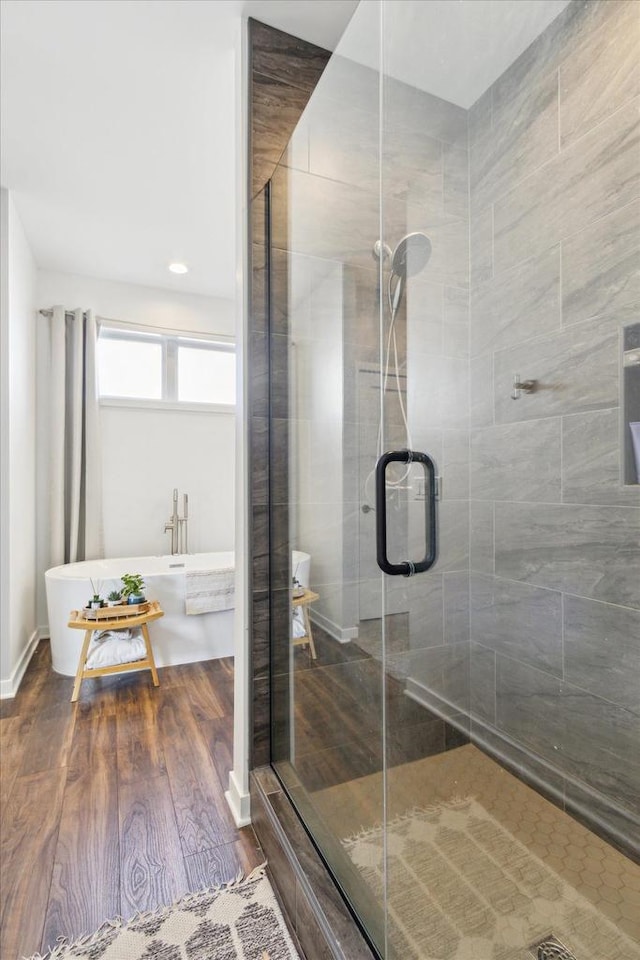 bathroom featuring wood-type flooring and shower with separate bathtub