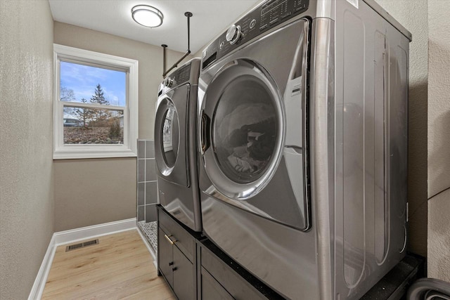 laundry room featuring independent washer and dryer and light hardwood / wood-style flooring