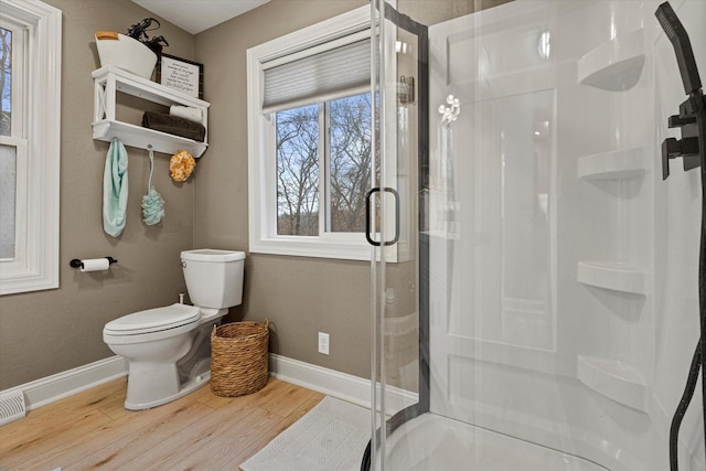 bathroom with a shower with door, hardwood / wood-style flooring, and toilet